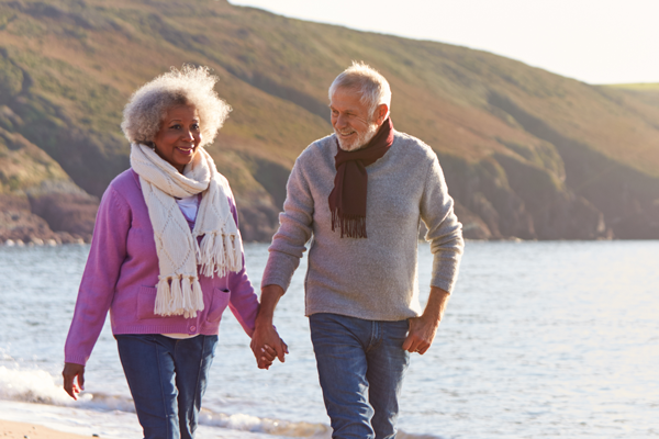 Older couple holds hands while walking along water